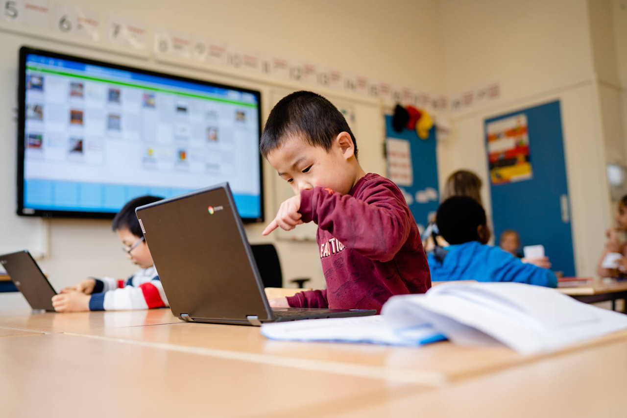 Aziatisch kindje wijst naar laptop